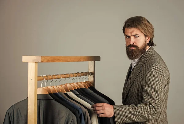 How do you like this. Man clothing in boutique. Man with suit. tailor in his workshop. Handsome bearded fashion man in classical costume suit. Man in custom tailored suit