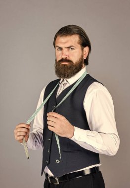 Beyaz gömlekli yakışıklı terzi çalışıyor. Antika mobilyalarla muhteşem bir atölye. Model için özel dikim takım elbisenin portresi. İş gömleği mağazada ölçü bandıyla dikilmiş.