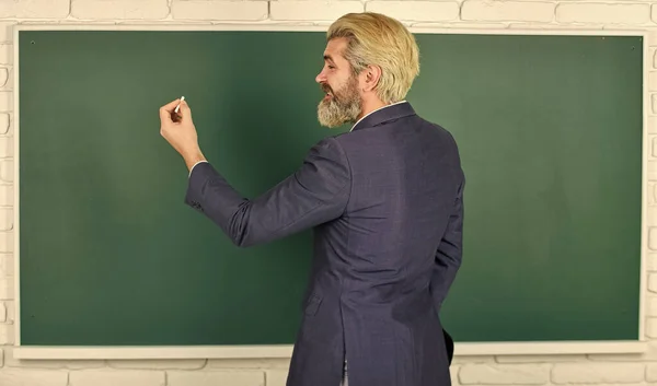 Every lesson changes person. Bearded man write on chalkboard. Senior teacher give lesson. Homework assignment. School lesson. Private lesson. Private teaching. School and education, copy space