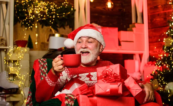 Wesołych Świąt. Brodatego starszego pana Mikołaja. Święty Mikołaj relaksuje się na krześle. Dostarczam prezenty. Zimowe wakacje. Starszy dziadek w domu. Koncepcja tradycji. Święty Mikołaj w pobliżu choinki — Zdjęcie stockowe