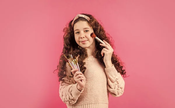 Criança bonita jogar cosméticos. Salão de beleza. infância feliz. moda e beleza. menina retro colocar maquiagem natural com escova. cabelo e cuidados com a pele. menina pequena desgaste vintage headband — Fotografia de Stock