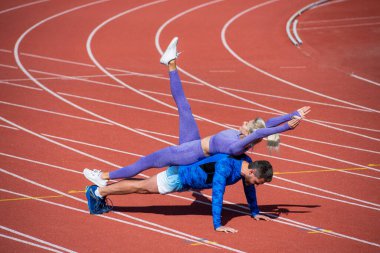 Fitness partnerleri yükseliyor. Atletik erkek ve seksi kadın yan yana. Stadyum arenasında erkek ve kadın koç. Sağlıklı bir yaşam tarzı. Güç ve güç. Spor çifti eğitimi.