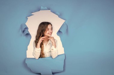 Kendine güvenen ve şık bir güzellik. Güzellik ve moda. Mutlu çocuğun sıradan bir görünüşü var. Modayı takip eden çocuğun mutlu bir çocukluğu var. Mavi arka planda küçük bir kız. Neşeli duyguları olan bir çocuk. Kadın kuaför salonu
