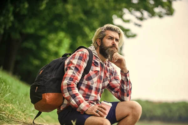 Inspirado hipster bonito. Inspiração. Homem ao ar livre com xícara de café. A beber café quente. Beba chá ou café. Homem com copo ao ar livre. Desfrutando da natureza à beira do rio. Cara com mochila relaxante — Fotografia de Stock