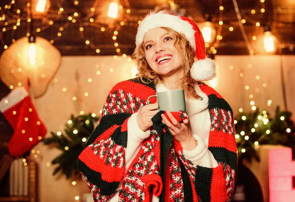 おはようございます。陽気な女性は居心地の良い...お祝いの時間を感じる。クリスマス気分だ。女性はココアを飲む。サンタ・ハットのミルクカップ。冬休みだ。モーニングコーヒー。新年明けましておめでとう。クリスマス — ストック写真
