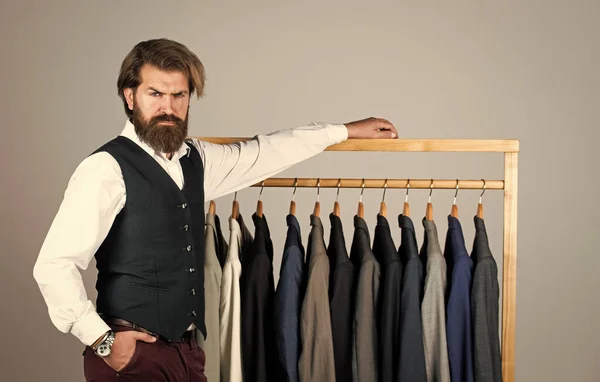 Man in custom tailored suit presenting expensive tailored tuxedo. Man clothing in boutique. Man with suit. tailor in his workshop. Handsome bearded fashion man in classical costume suit — Stock Photo, Image