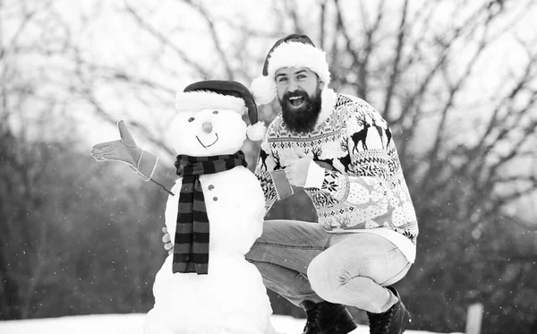 Χειμερινές διακοπές. Ο άνθρωπος έφτιαξε χιονάνθρωπο. Χίπστερ με γενειάδα έξω. Άντρας με καπέλο Αϊ-Βασίλη διασκεδάζει έξω. Guy χαρούμενο πρόσωπο χιονισμένο φόντο της φύσης. Χειμερινοί αγώνες. Χειμερινή δραστηριότητα. Διασκέδαση και διασκέδαση — Φωτογραφία Αρχείου