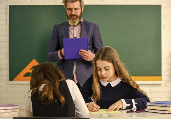 Studenten testen. Pedagoog. Ze in de gaten houden. Leraar en kinderen klaslokaal. Dagelijks schoolleven. Terug naar school. Hulp en ondersteuning. Kinderen en leraar. Gerichte en geconcentreerde studenten. Controleproces — Stockfoto