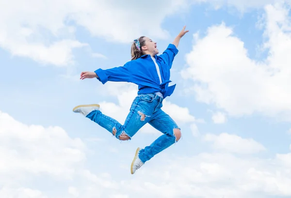 Menina adolescente vestindo roupas de moda casual pulando alto no fundo do céu, energia — Fotografia de Stock