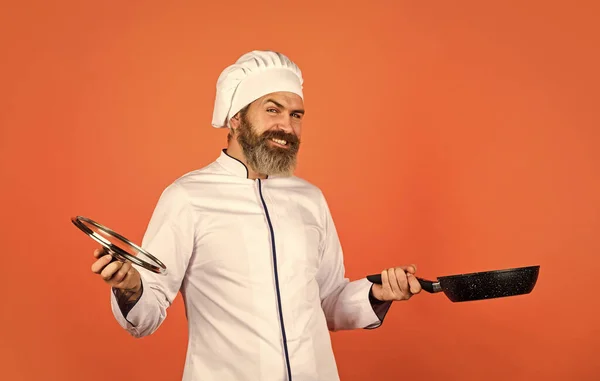 Gezond ontbijt. Man met koksmutsen op keuken. Koken voedsel concept. Braadpan vasthouden. beste kwaliteit. baardkok in uniform met gereedschap. Een man met een baard houdt een kookpan vast. bereiden van voedsel in de keuken — Stockfoto