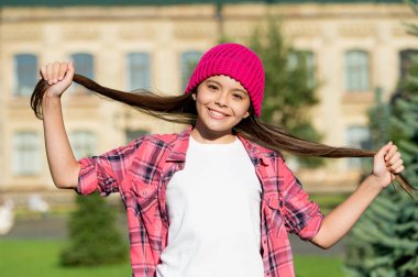 Bugün saçını tedavi et. Mutlu kız dışarıda uzun saçları tutuyor. Küçük çocuğun güzel görünüşü. Kuaför salonu. Şampuanlama ve kondisyon. Saç bakımına iyi gelir.