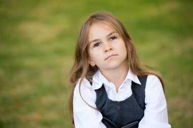 Uzun saçlı, ciddi bir çocuk. Moda okulu üniforması giyiyor.