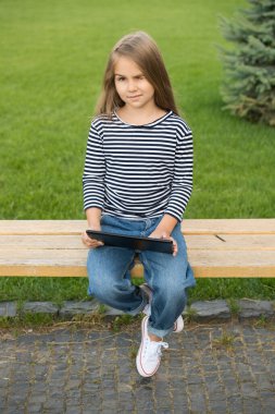 Dijital öğrenme ve çalma. Küçük çocuk park bankında otururken tablet kullanıyor. Mobil teknoloji. 3G mi? 4G mi? Taşınabilir mobil cihaz. Modern yaşam tarzı. Çevrimiçi okul ve evde eğitim. Uzaklık eğitimi