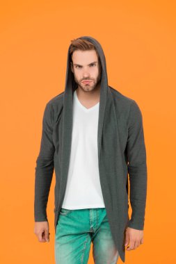 Yakışıklı ve sıradan biri. Yakışıklı adam sarı arka plan. Genç adam kapüşonlu sweatshirt giyiyor. Moda görünümlü yakışıklı bir manken. Moda ve tarz. Yakışıklı ve kendinden emin.