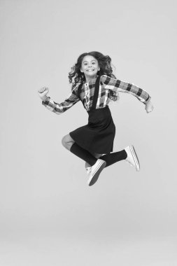 Eğlence zamanı. Aktif kız özgürlüğü hisseder. Eğlence ve zıpla. Mutlu çocuklar günü. Sıçrama konsepti. Zorla gir. İç enerjiyi hisset. Sarı arka planda atlayan uzun saçlı bir kız. Tasasız çocuk yaz tatili