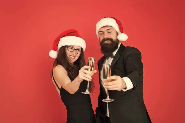 Új év, új célok. üzletember és lány pezsgőt isznak. Karácsonyi buli. A szerelmesek ünnepelik az új évet. szmokingos férfi női télapósapkával. Boldog karácsonyt és éljenzést mindenkinek! — Stock Fotó