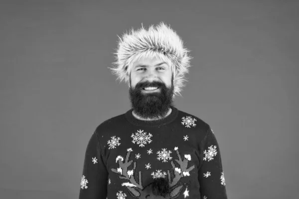 Karácsonyi móka. Boldog hipszter készen áll a karácsonyi bulira. téli ünnepség. hideg időjárás divat. Boldog új évet! Szakállas férfi, vörös háttérrel. vicces férfi szakállal kötött pulóverben — Stock Fotó