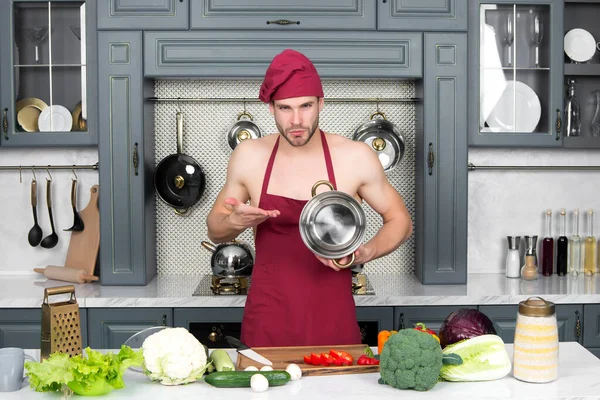 Man chef-kok in schort op kale romp wijzen op steelpan — Stockfoto