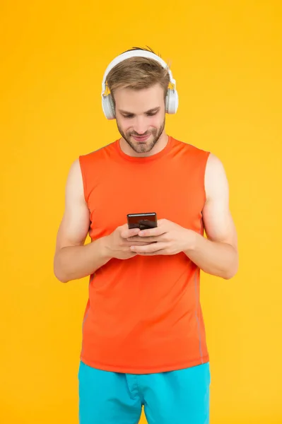 Χαρούμενα γενειοφόρος άνθρωπος ακούστε μουσική σε ψηφιακά ακουστικά χρησιμοποιώντας το κινητό τηλέφωνο app φορώντας σπορ ρούχα για προπόνηση, κοινωνικό δίκτυο — Φωτογραφία Αρχείου