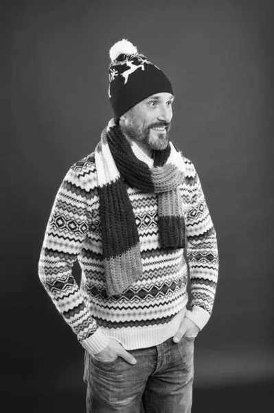 冬のスタイルで髭の男。白人男性は暖かい服を着ている。冬のトレンド。ニット帽スカーフとセーター。冬のニットウェア。ニットウェアアクセサリー。成熟した男の赤の背景。寒い天候の概念 — ストック写真