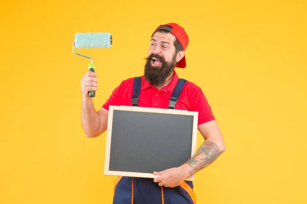 Щасливий бородатий чоловік художник у костюмі котла з використанням інструменту для малювання стіни і тримання дошки для копіювання простору реклами, маркетингової реклами — стокове фото