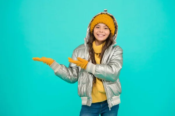 Menina adolescente sorridente em casaco acolchoado ou puffer pronto para passar férias de inverno e férias no conforto e calor apresentando produto, espaço de cópia, estância de esqui — Fotografia de Stock