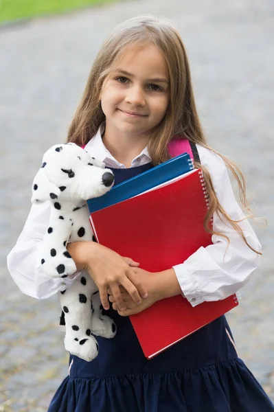 Glückliches kleines Kind in Schuluniform hält Lernbücher und Spielhundefreund, Freundschaft — Stockfoto