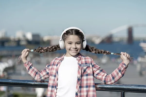 Girl child listen music outdoors with modern headphones. Listen for free. Get music family subscription. Access to millions of songs. Enjoy music everywhere. Best music apps that deserve a listen