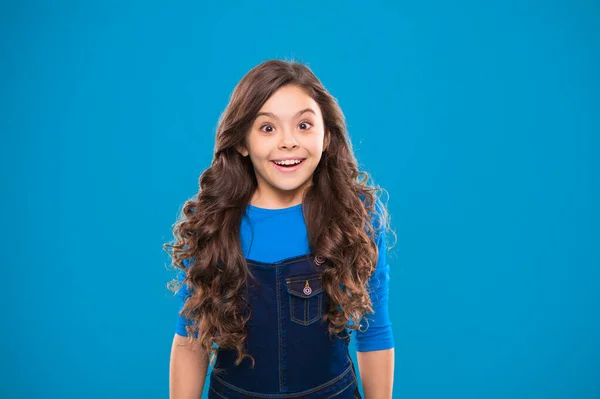 Kid menina longo cabelo brilhante saudável usar roupas casuais. Menina animado rosto feliz. Kid feliz bonito rosto se sente animado fundo azul. Uma excitação sincera. Momentos emocionantes. Emoção de excitação — Fotografia de Stock