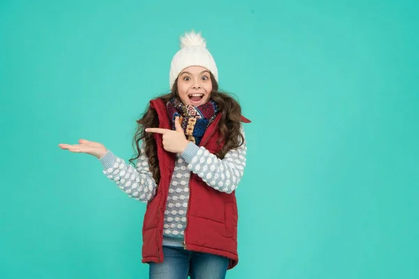 Vrolijk kind in warme winter kleding van gebreide hoed sjaal en trui op nieuwjaar vakantie presenteren product, kopieer ruimte voor reclame, Kerstmis winkelen — Stockfoto