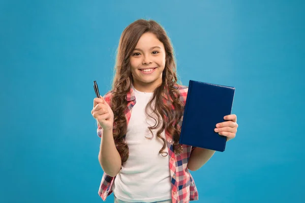 Είμαι έτοιμος για το σχολείο. Το έξυπνο παιδί κρατάει στυλό και σημειωματάριο. Κορίτσι χαριτωμένο χαρούμενο πρόσωπο θέλει να μελετήσει μπλε φόντο. Παιδί κορίτσι κρατά βιβλίο και στυλό. Επιστροφή στο σχολείο έννοια. Σχολική εργασία — Φωτογραφία Αρχείου