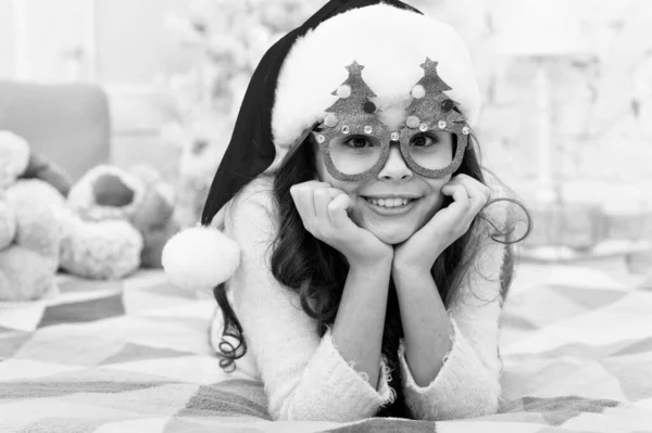 Feliz año nuevo. Lista de deseos. Ambiente de vacaciones. Espíritu navideño. Vacaciones de año nuevo. Niños pequeños usan sombrero de santa celebrar el año nuevo en el fondo interior decorado en casa. Niña en el dormitorio con juguetes —  Fotos de Stock