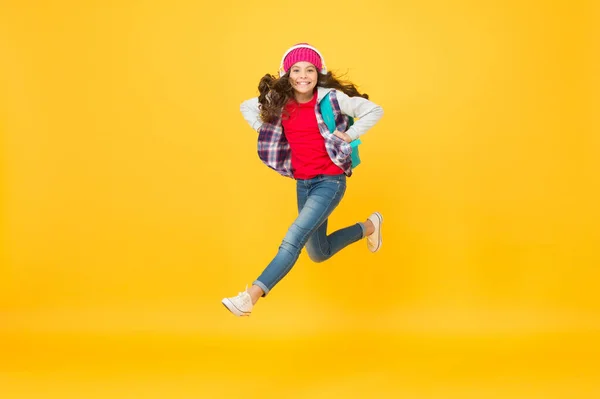 Criança pequena ativa correr com saco de viagem ouvindo música em fones de ouvido fundo amarelo, viajando — Fotografia de Stock