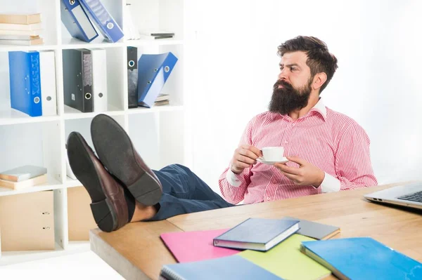 Sidottu liikemies rentoutua työpaikalla juo kuumaa teetä tai kahvia modernissa toimistossa, energia — kuvapankkivalokuva