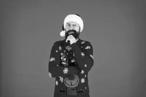 Gott nytt år. Glada hipster rolig stickad tröja. varma kläder i kallt vinterväder. julstämning. skäggig man Tomte hatt röd bakgrund. God jul, då. redo för julfest — Stockfoto