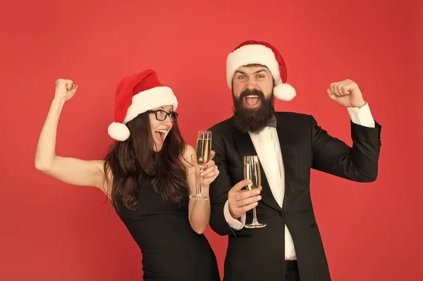 Pareja enamorada en la fiesta. Feliz año nuevo. Hombre barbudo en esmoquin y chica elegante vestido bebiendo vino espumoso y bailando fondo rojo. Fiesta de invierno. Gente alegre. Feliz navidad. Fiesta de oficina — Foto de Stock