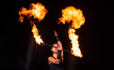 Parıltılı ateş performansı sırasında karanlıkta dönen seksi sanatçı sopaları çeviriyor.