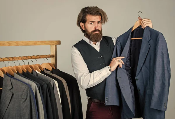 Uomo in abito su misura che presenta smoking su misura. Vestiti da uomo in boutique. sarto nel suo laboratorio. Bello uomo di moda barbuto in costume classico. Alla ricerca di ispirazione progettuale — Foto Stock