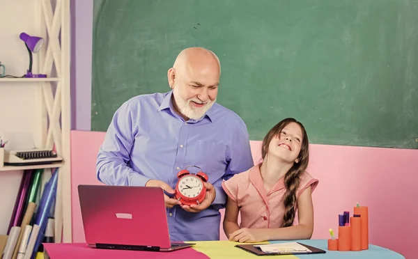 Preoccupati del tempo. piccola ragazza con uomo tutor studio sul computer. insegnante maturo aiutare allievo con orologio. tempo di studiare. lezione di scuola online. allarme di rottura. Buongiorno. educazione blogging. Ritorno a scuola — Foto Stock