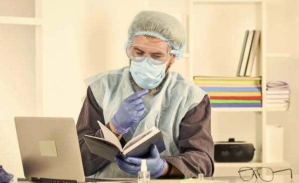 Doktorn studerar. Ett utbrott av Coronavirus. Senaste vetenskapliga rön och kunskap om coronavirus sjukdom. Lär dig att skydda dig själv. Man läser bok. Medicinsk forskning. Arbetstagare i skyddsutrustning — Stockfoto