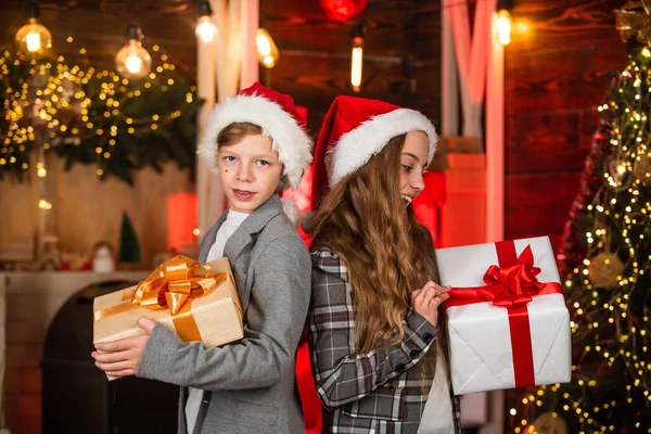 Family Christmas tradition. Kids lovely friends meet Christmas holiday. Sister and brother with gift boxes. Dreams come true. Festive atmosphere christmas eve. Boy and girl santa claus hats — Stock Photo, Image