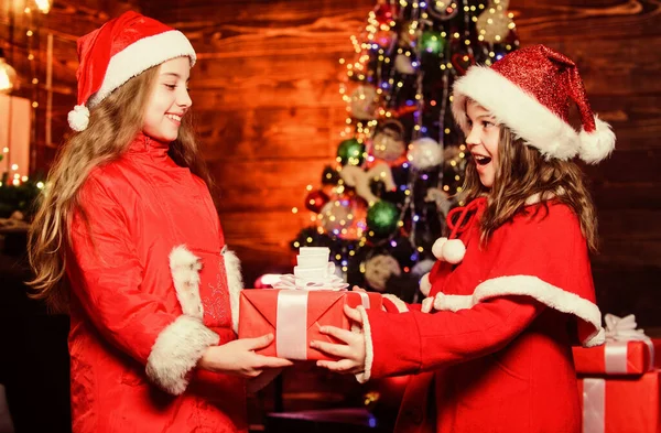 Festive atmosphere christmas day. Girl santa claus costume hold christmas gift box. Prepare surprise gift. Open gift. Happy moments. Kid giving christmas gift to sister. Congratulating nearest