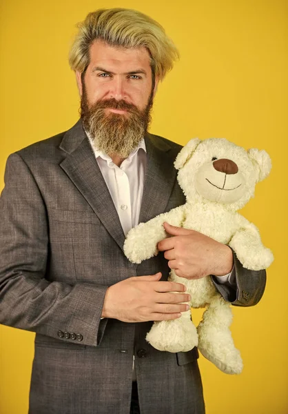 Friendly relations. Imaginary friend. Still childish in soul. Happy businessman hug teddy bear yellow background. Bearded man with toy friend. Friend and friendship. Adoption and adoptive parent — Stock Photo, Image