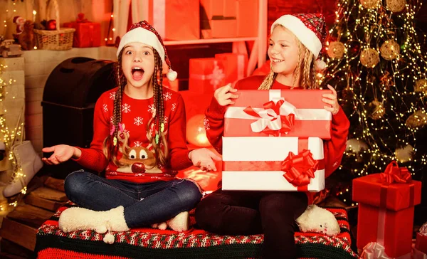 Niñas felices en el árbol decorado. celebración de Navidad. vacaciones en familia. Fiesta de Año Nuevo. niños con sombrero rojo de santa. niños con caja de regalo. Recuerdos brillantes. Viendo programas de Navidad juntos —  Fotos de Stock