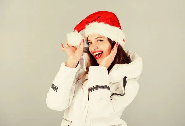 A lány fehér kabátot és télapó sapkát visel. A kabát extra szigeteléssel rendelkezik, hogy megvédje a testet az éles téli időjárástól. Fehér dzseki. Várom a fagyos karácsonyi napokat. Érzelmes női smink arc. Mikulás lány — Stock Fotó