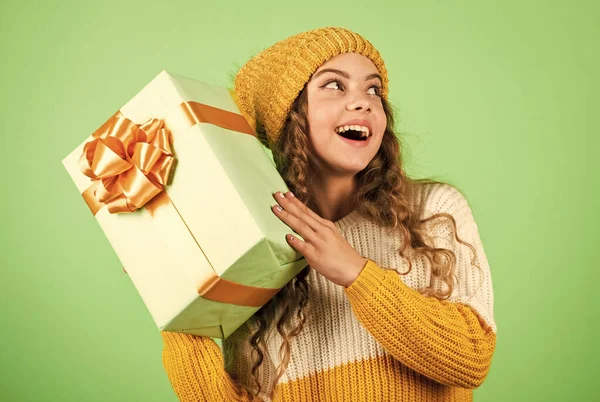 Ajándékdoboz a kölyöknél. Boldog téli ünnepeket! Vidám kislány kötött sapkát és pulóvert. Születésnapi meglepetés. Bevásárlóközpont koncepció. Születésnapi ünnepség ötlet. Jó hangulat. Születésnapi hagyomány — Stock Fotó