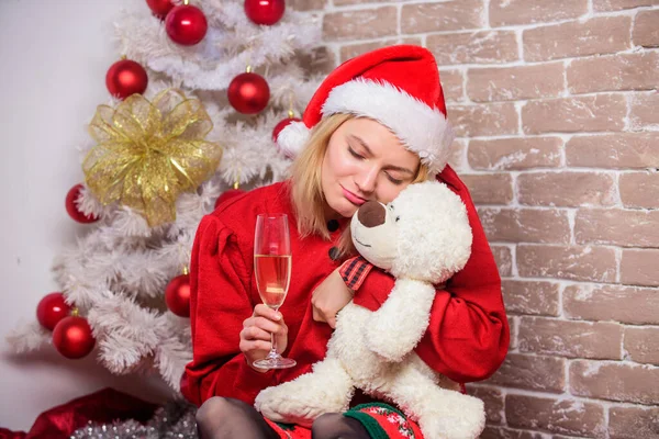 sleepy mood. xmas party mood. celebrate new year together. merry christmas to you. family holiday. winter season. woman at decorated tree. xmas presents. happy santa girl drink champagne toy bear