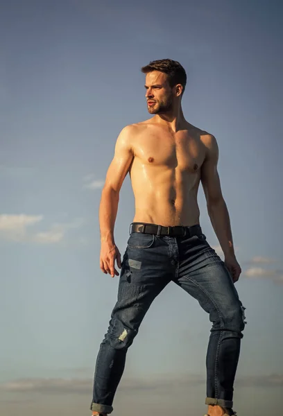 Torso nudo muscolare. Sei pacchi petto muscoloso. Uomo all'aperto sfondo cielo blu. Tendenze estive. Il concetto di bellezza maschile. Giornata calda. Il bel macho atletico indossa pantaloni di jeans. Corpo muscolare. Modello fitness — Foto Stock