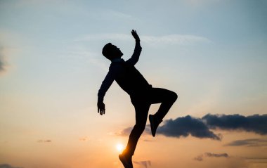 Özgür olmak için. Özgür adam dans ediyor. Mutluluk. İlham lazım. İnsan motivasyonu hisseder. Enerji dolu. Dansçı silueti gökyüzü arka planında. Güven ve başarı. Gelecek konsepti