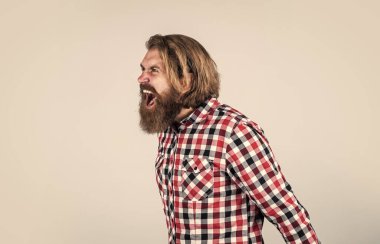 Büyük bir öfke hissediyorum. Kareli gömlekli kızgın sakallı adam bağırıyor. Sakallı hippi portresi. Uzun, gür sakallı ve bıyıklı bir adam. Yakışıklı, kendine güvenen bir adamın mükemmel bir saç stili var.